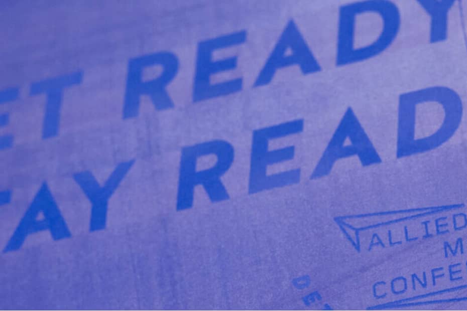 bold blue letters reading "Get Ready Stay Ready" over purple canvas posted on wall`