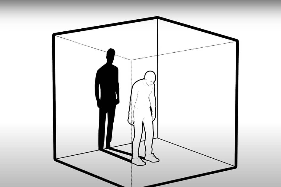 A black and white drawing of a person standing slouched over and casted shadow behind them, all encapsualted in a cube.